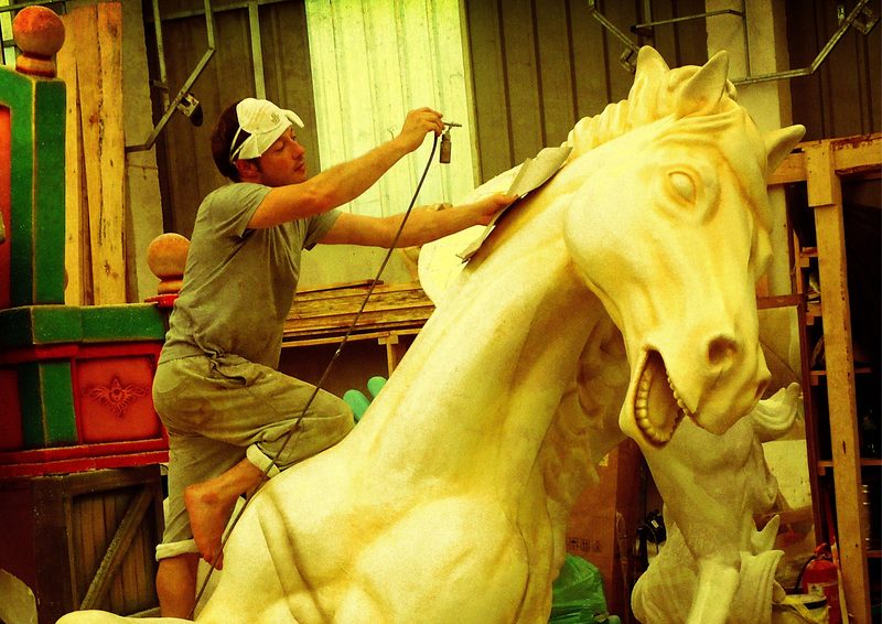 Escultor tallando un caballo de gran tamaño en el taller.